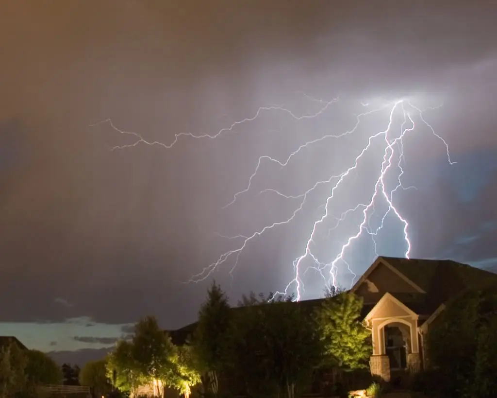 A dramatic lightning display above a residential area during a night-time thunderstorm.